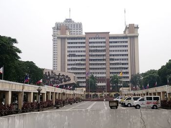 Cars on road by buildings against clear sky