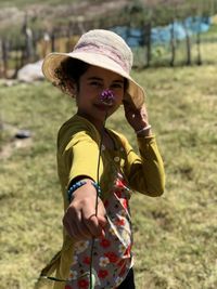 Full length of boy holding hat on field