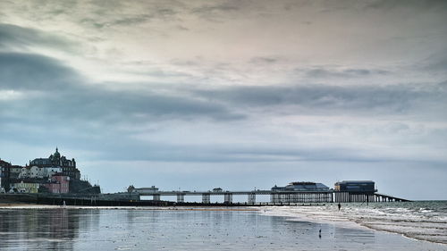 Pier at beach cloudy sky