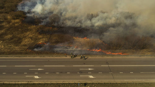 Massive fire, dry grass lanes in fire, firefighters at work, disaster, ecological catastrophe