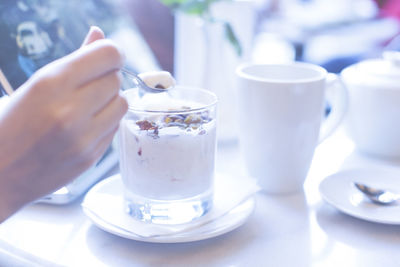Cropped image of woman hand with granola yoghurt at cafe