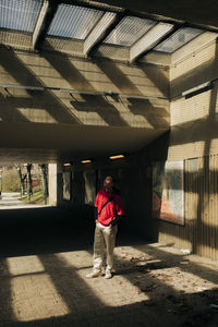 Young man standing in sunlight below underpass