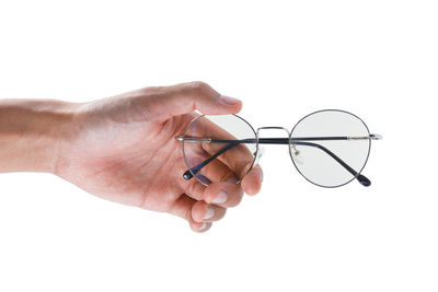 Close-up of hand holding eyeglasses against white background