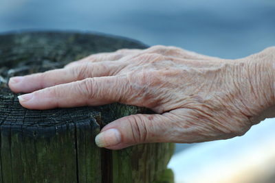 Close-up of wrinkled hand on wood