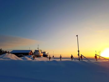 Snow covered land against sky during sunset