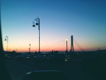 Cars on road against clear sky during sunset