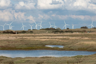 Wind turbines on land against sky