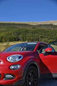 Red car on landscape against blue sky