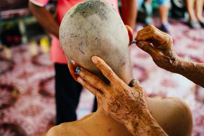 Cropped hand of barber shaving hairs of customer