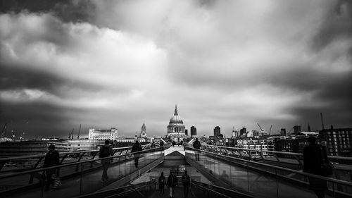 Scenic view of bridge leading towards old building against cloudy sky