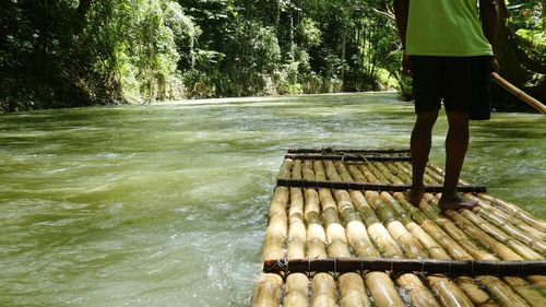 Low section of man on bamboo raft during river rafting