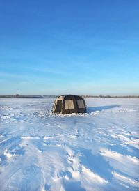 Scenic view of snowcapped field against blue sky