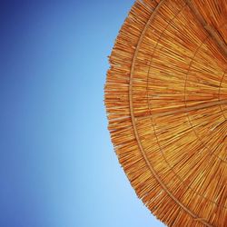 Low angle view of parasol against clear blue sky