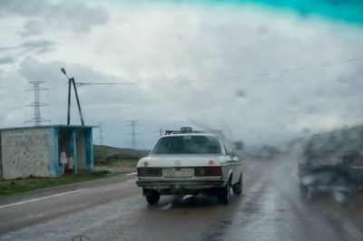 Cars on road against sky in city