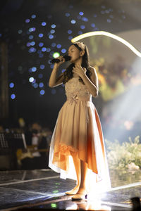 Low angle view of young woman standing against waterfall