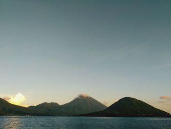 Scenic view of sea and mountains against clear sky