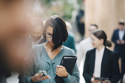 Female entrepreneur using smart phone outside office