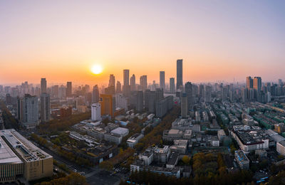 Aerial view of modern buildings in city against sky during sunset