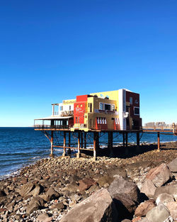 Houses by sea against clear blue sky