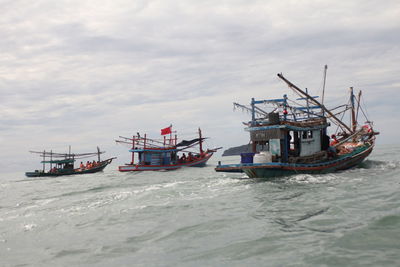 Fishing boat moored in sea against sky