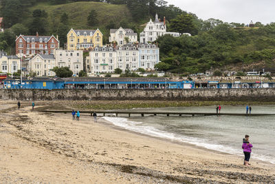 People on beach against buildings in city