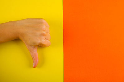 Close-up of hands against orange background