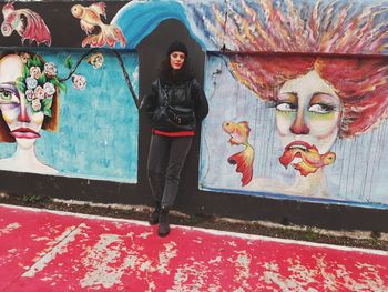 Full length of woman with multi colored graffiti on wall