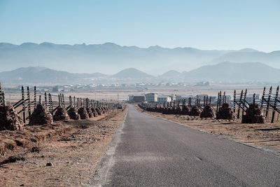 Road leading towards mountains against clear sky