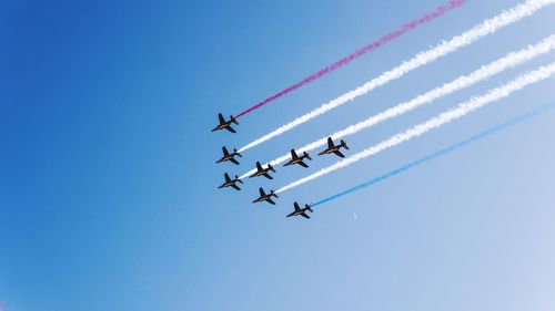 Low angle view of airshow in clear blue sky