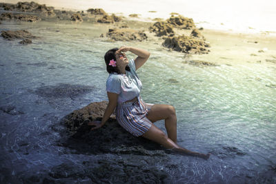 Woman sitting on rock at beach