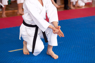 Low section of man practicing karate on carpet