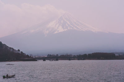 Scenic view of lake by snowcapped mountains against sky