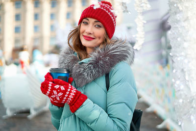 Portrait of smiling young woman wearing knit hat standing outdoors