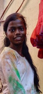 Portrait of smiling young woman standing against wall