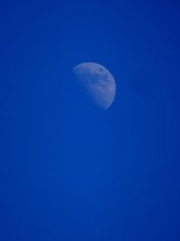 Low angle view of moon against clear blue sky