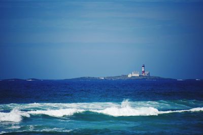 Lighthouse by sea against sky