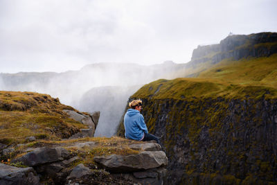 Man sitting on rock against mountains