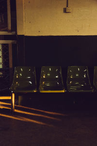 Close-up of empty chairs and table against wall