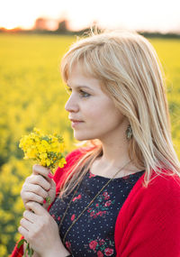 Close-up of beautiful young woman with flowers in field