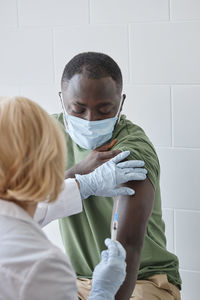 Doctor injecting covid-19 vaccine on patient arm in clinic