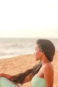 Portrait of young woman sitting at beach