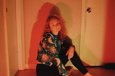 Portrait of woman standing against wall at home