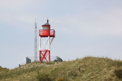 Lighthouse on field against sky