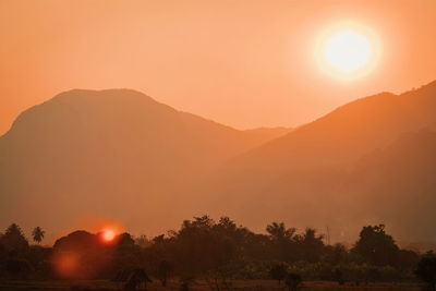 Scenic view of silhouette mountains against orange sky