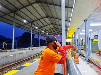 Man standing on train at railroad station