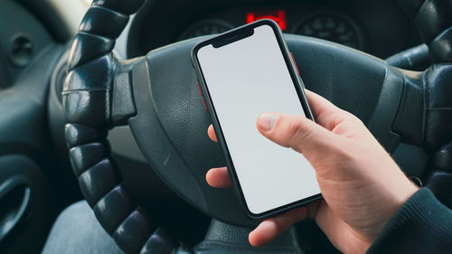 Midsection of man using mobile phone in car