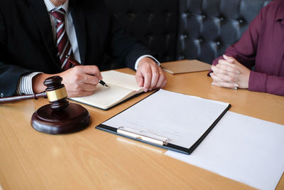 Midsection of judge and client discussing on table