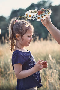 Close-up of girl holding flower on field