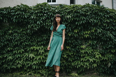 Portrait of young woman standing against plants