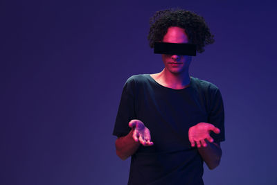 Young man wearing vr glasses against blue background